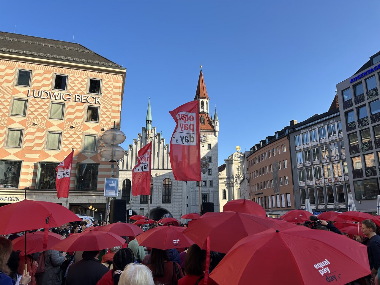 Stimmungsbild vom Equal Pay Day 2025 am Münchner Marienplatz mit roten Regenschirmen